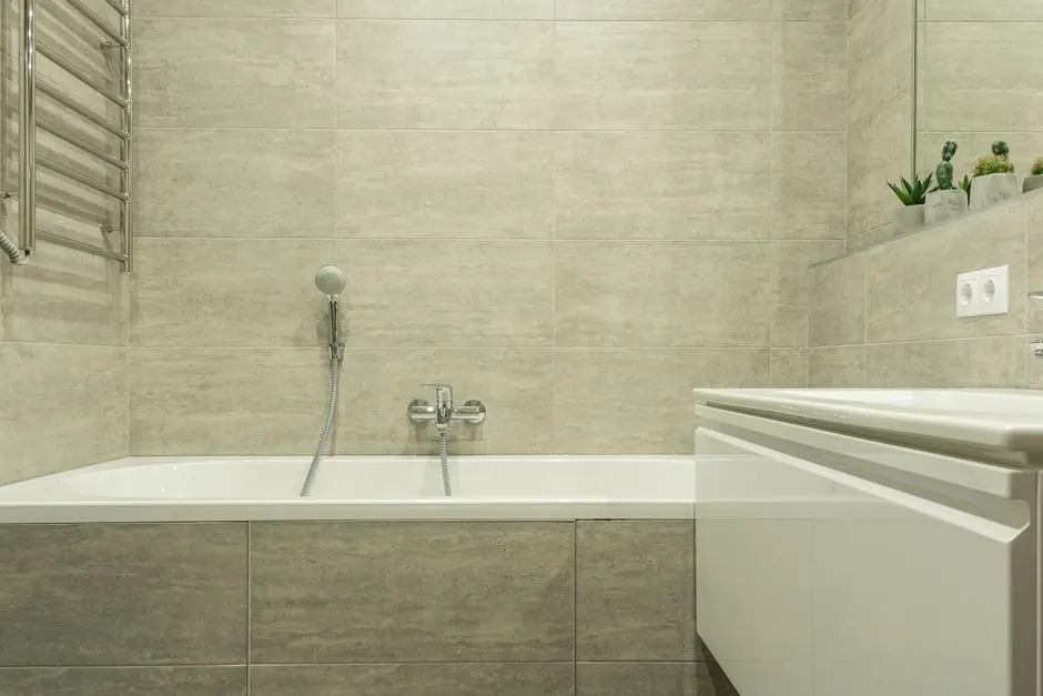 A clean and modern bathroom interior showcasing a ceramic bathtub and stylish tiles.